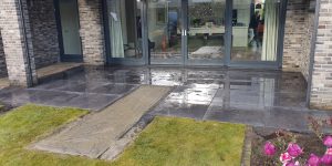 Strak gelegd antraciet terras met grasstroken voor een woning