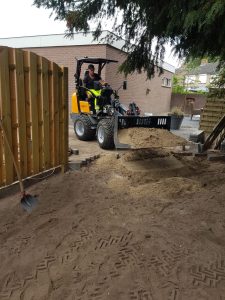 Wiellader aan het werk naast een nieuwe schutting